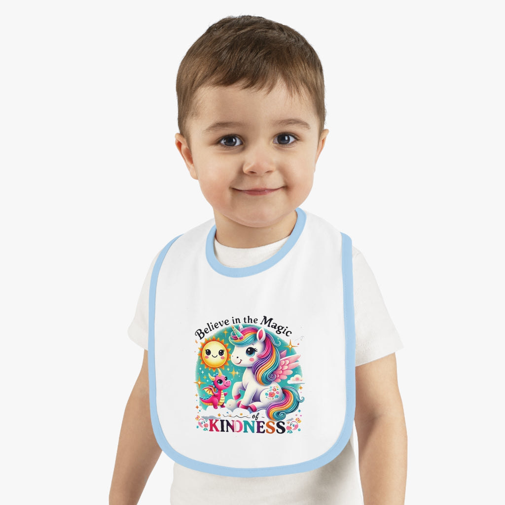 Baby in a soft, stylish bib with unicorn and "Believe in the Magic of Kindness" text.
