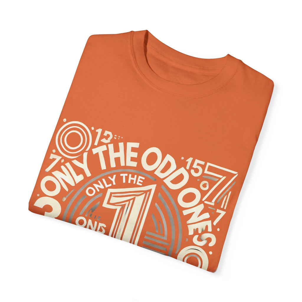 Unisex garment-dyed T-shirt folded, "Only the Odd Ones Can Be Number One" graphic in orange.