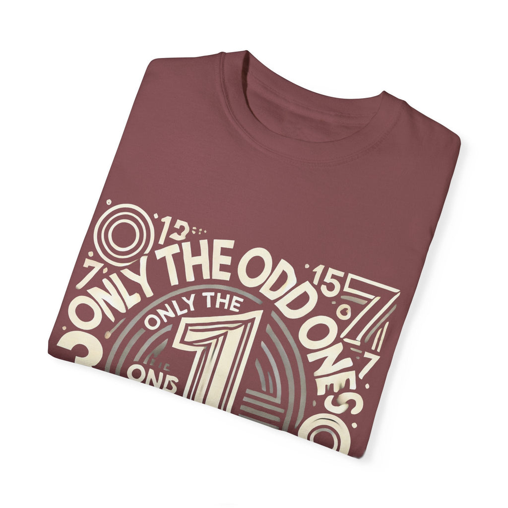 Unisex garment-dyed T-shirt with "Only the Odd Ones Can Be Number One" design, folded, on a white background.