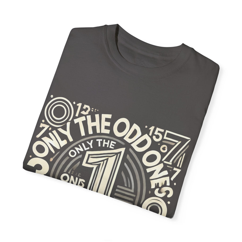 Unisex garment-dyed T-shirt with "Only the Odd Ones Can Be Number One" graphic design, folded.